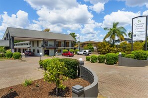 Experience the charm of Country Motel Ipswich, featuring a flat roof, covered porch, and beautifully landscaped grounds with a paved driveway.