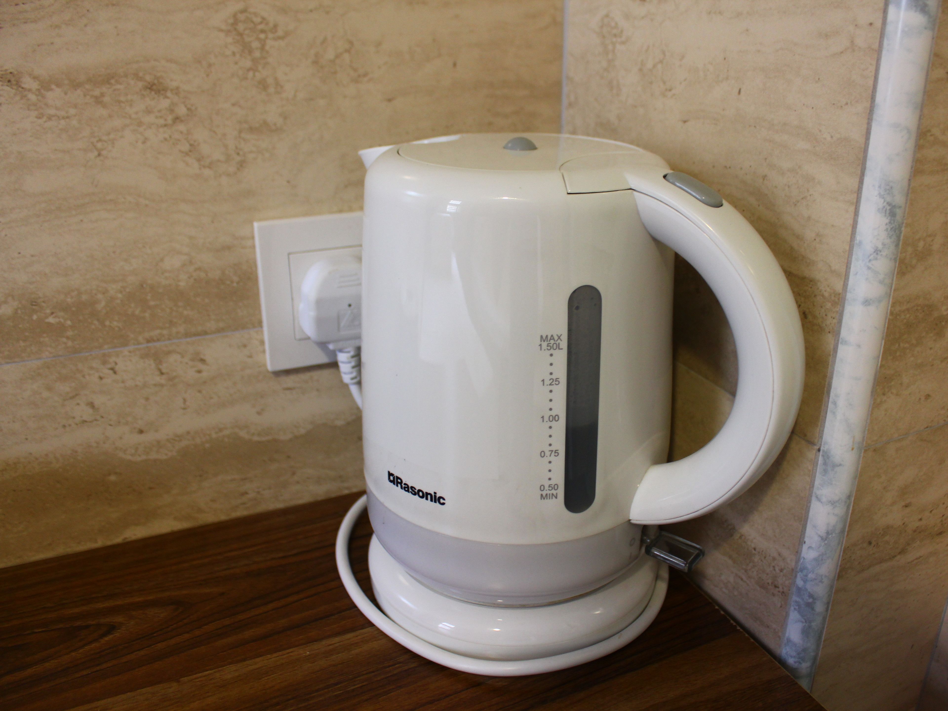 A white electric kettle with a digital display on a wooden countertop.