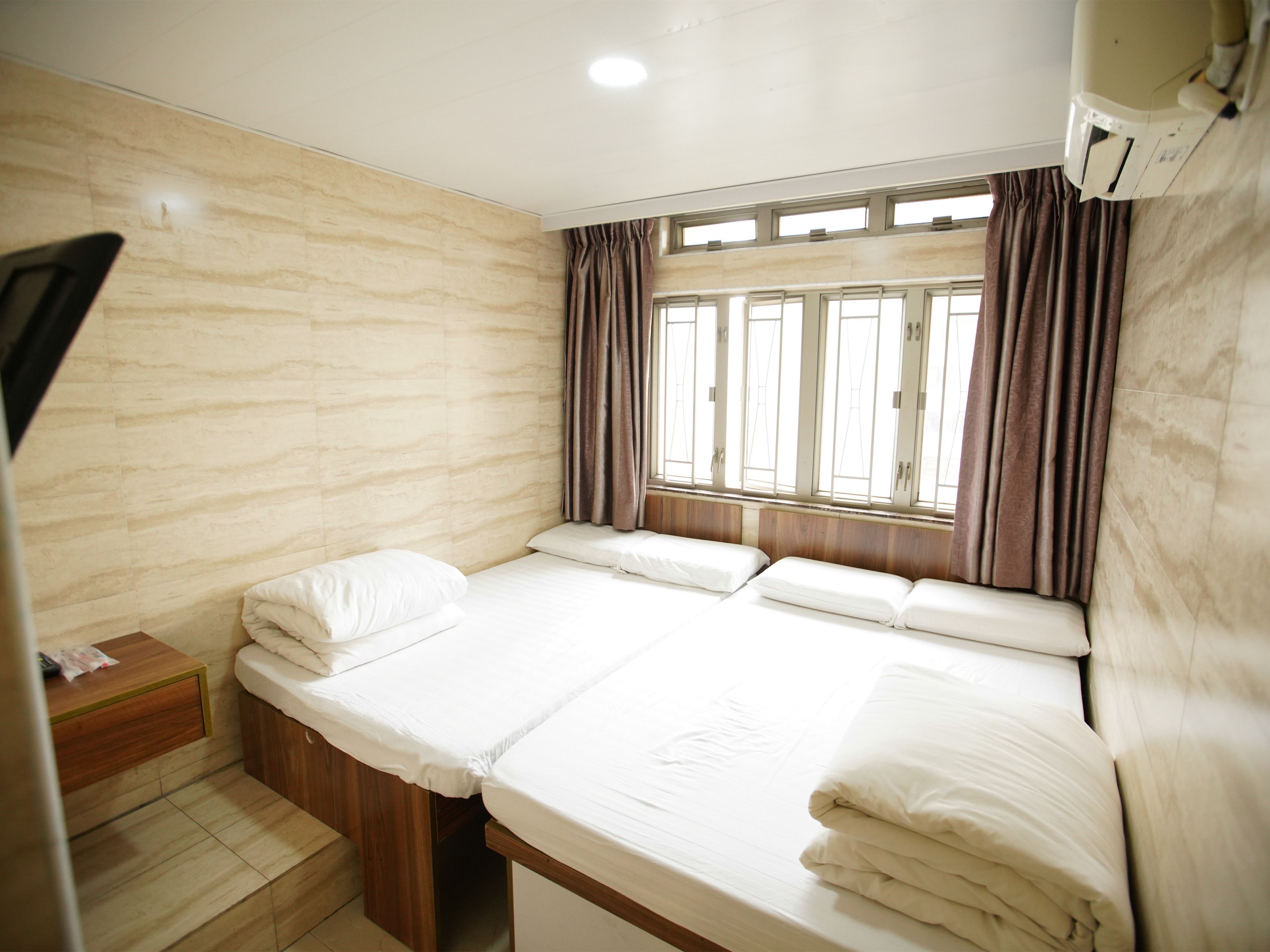 A single bed with a wooden headboard, a nightstand, and a window with curtains.
