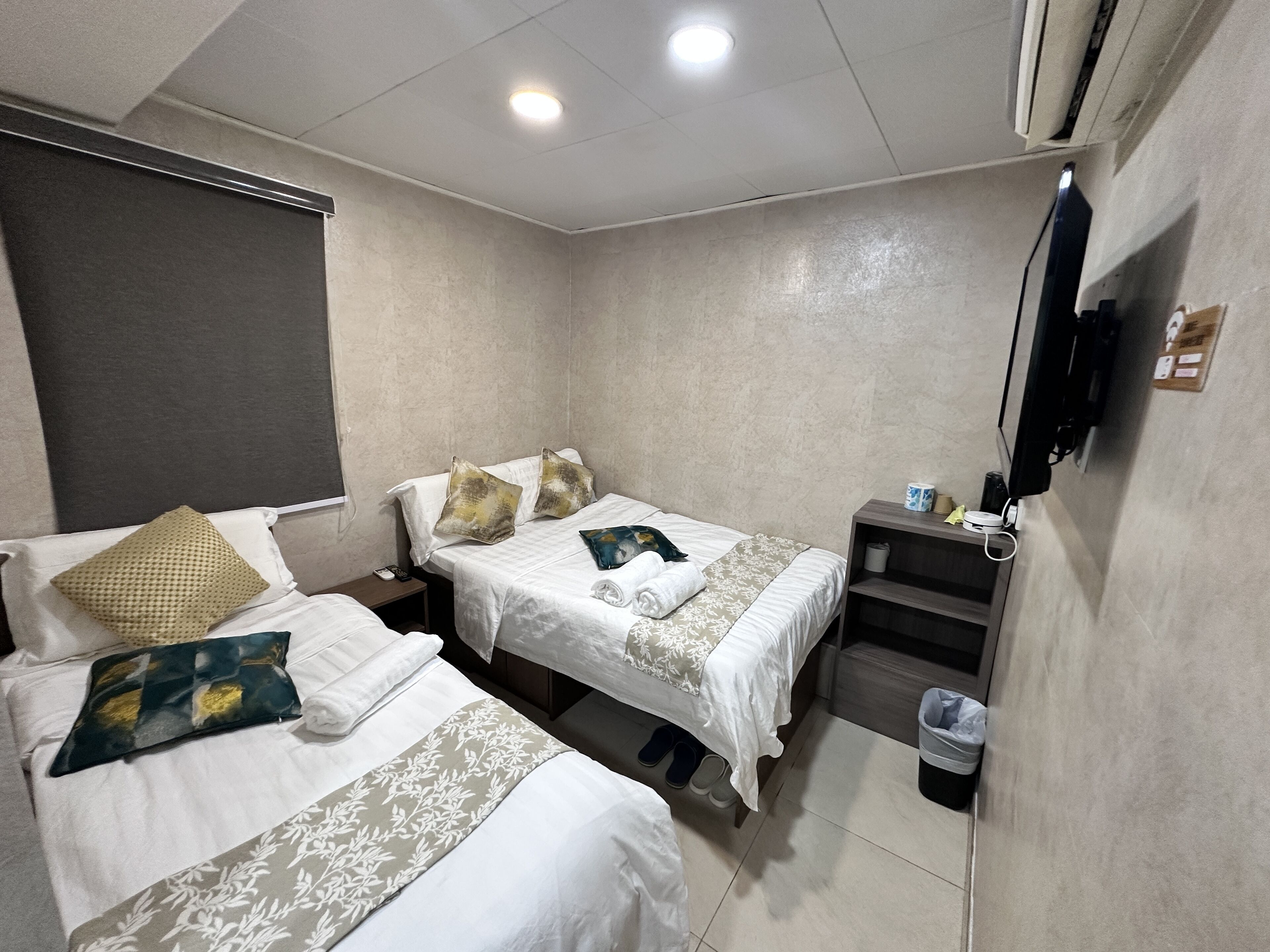 Habitación de hotel con dos camas, un televisor, una mesita y un cesto de basura.