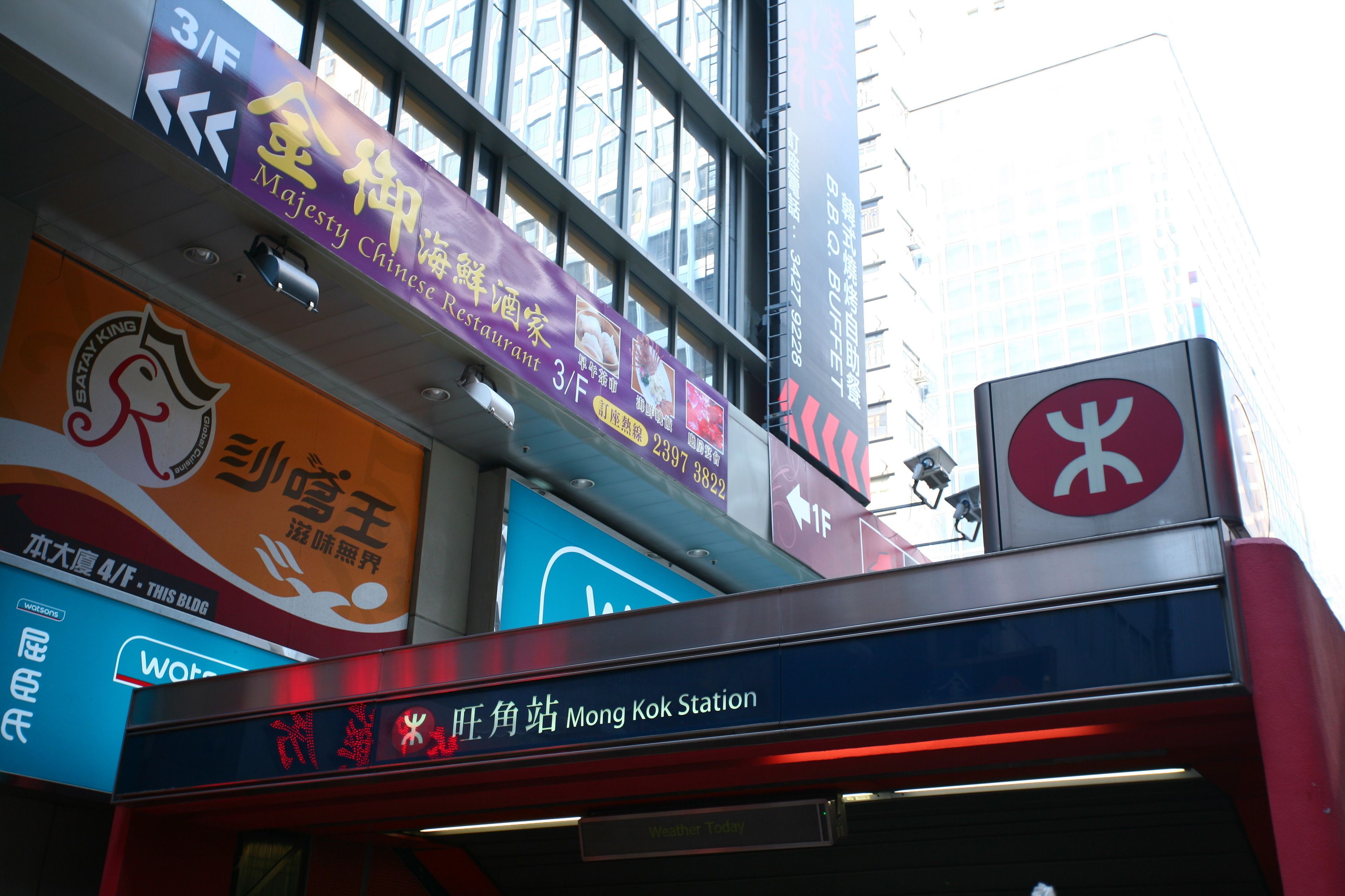 A sign for a restaurant with a large logo and multiple languages.