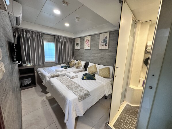 A hotel room with two beds, a shower, and a small seating area.
