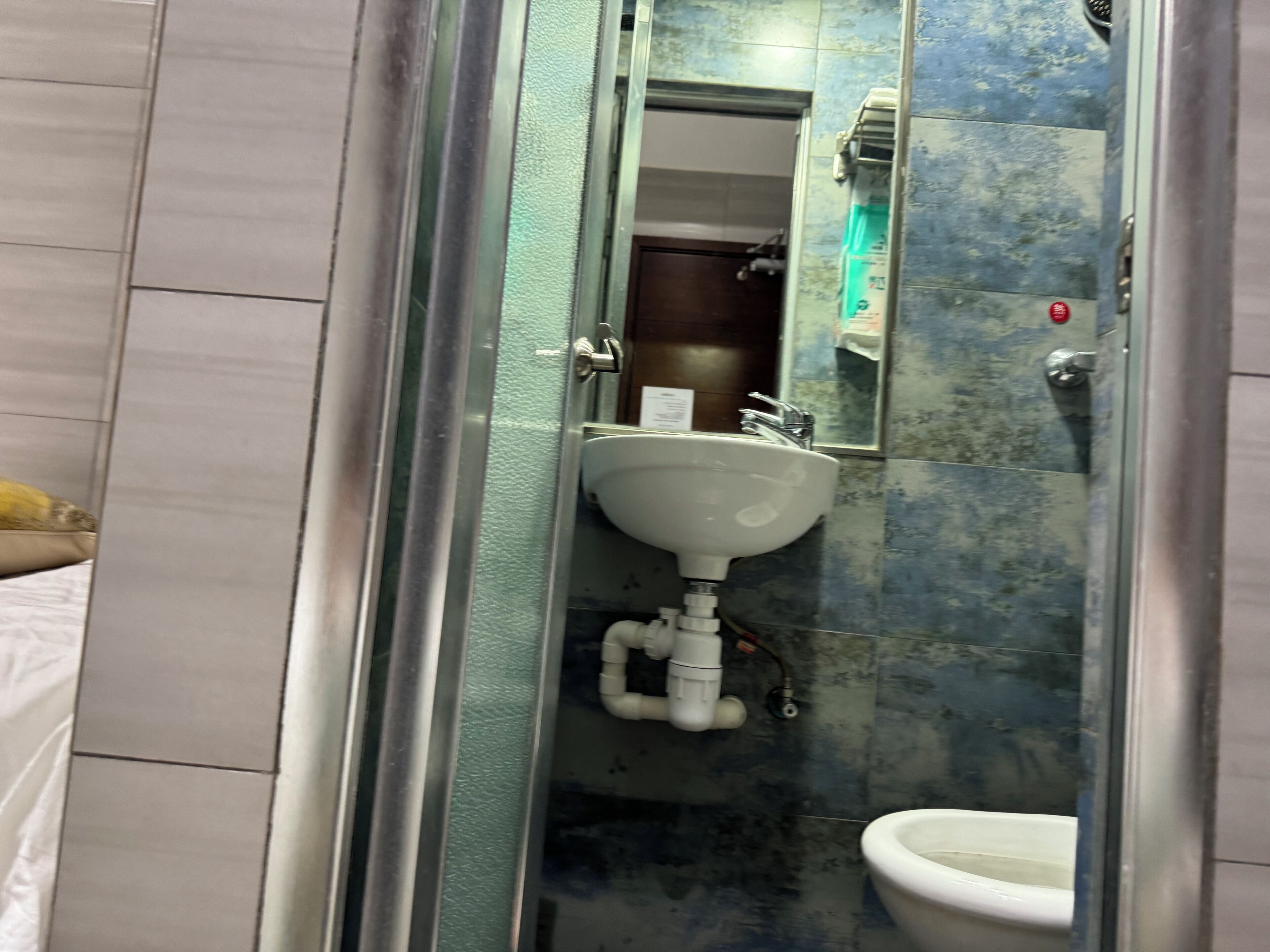 A bathroom with a glass partition, a sink, a mirror, and a toilet.