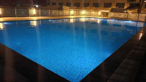 Una piscina con borde de azulejos y una zona circundante oscura.