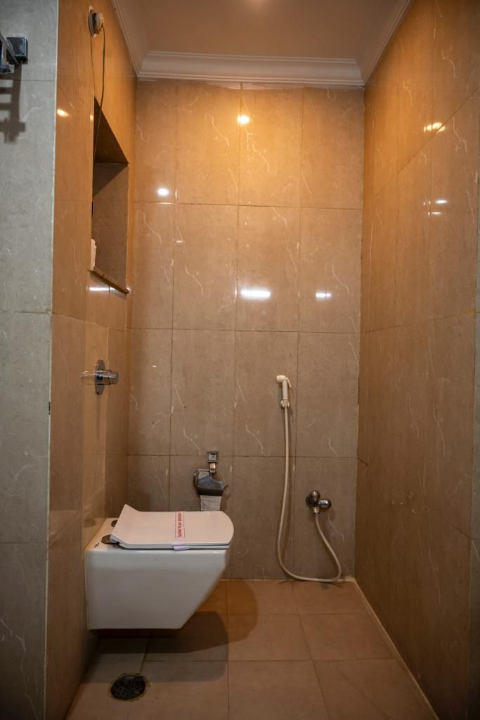 A small, enclosed shower area with a white toilet and a handheld showerhead.