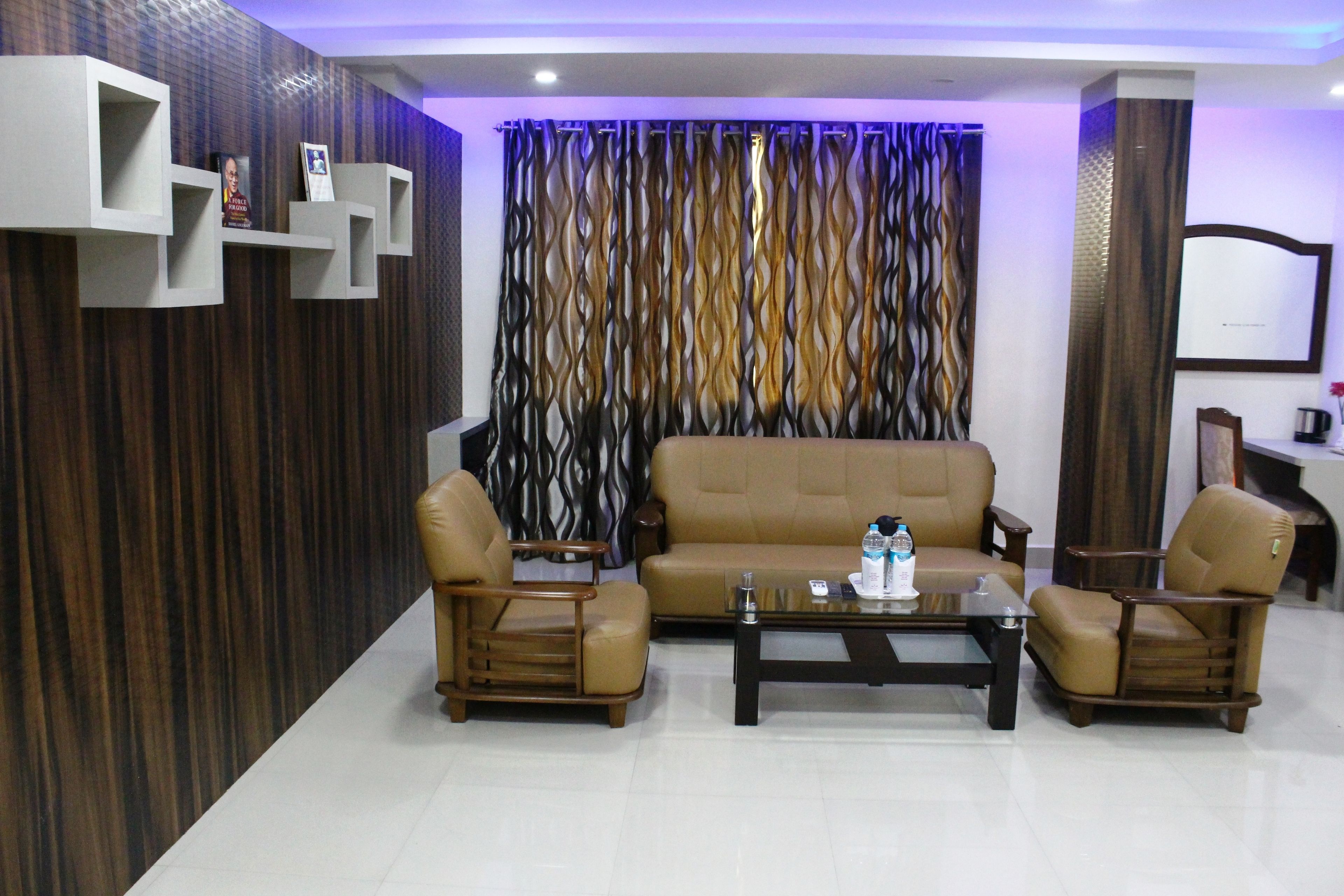 A living room with a sofa, two armchairs, a coffee table, and decorative shelves.