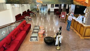 Un vestíbulo de hotel con un sofá rojo, una mesa de recepción y una estatua de Buda.