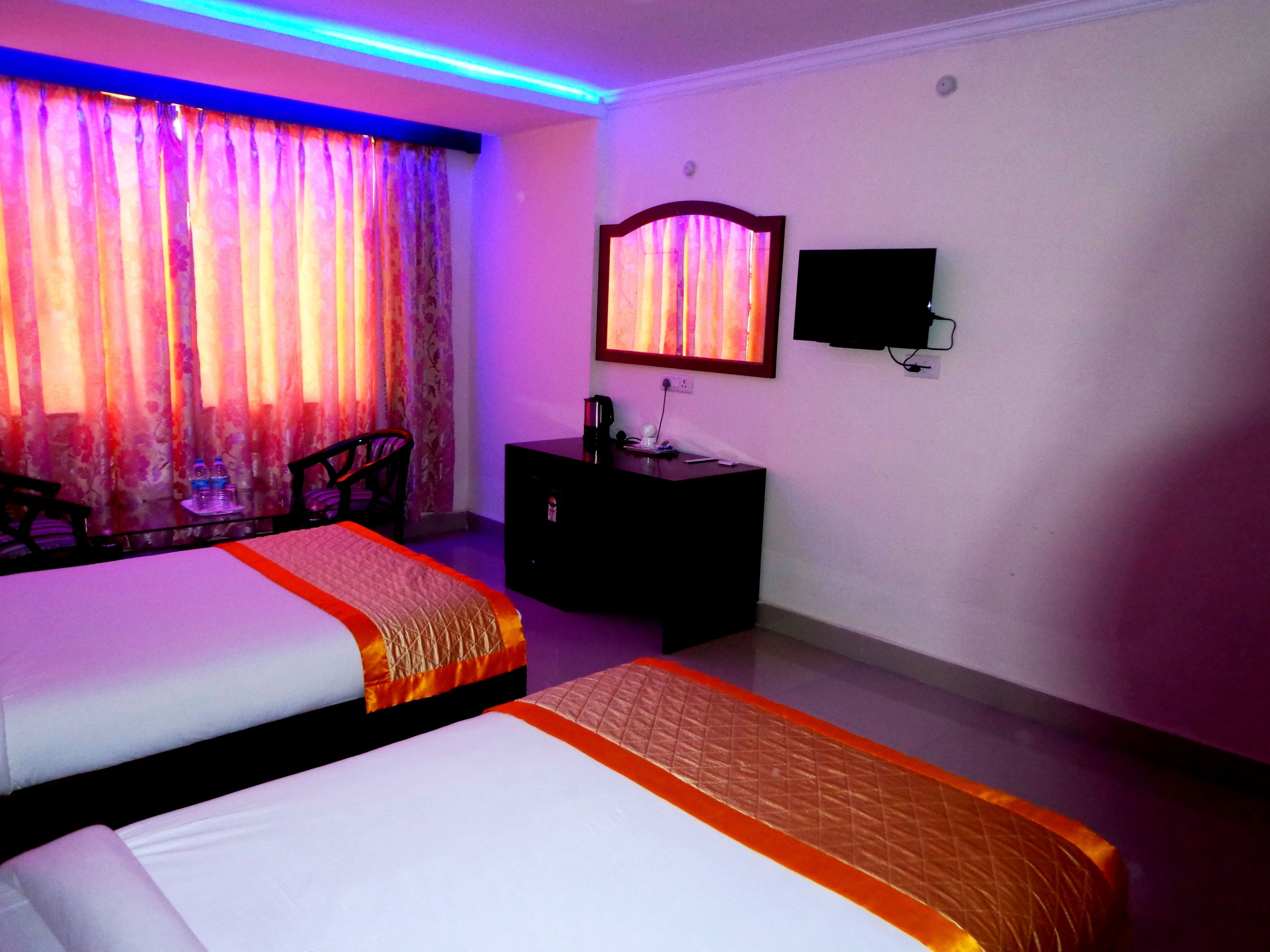 Une chambre d’hôtel avec deux lits, un bureau, une chaise, un miroir et une télévision.