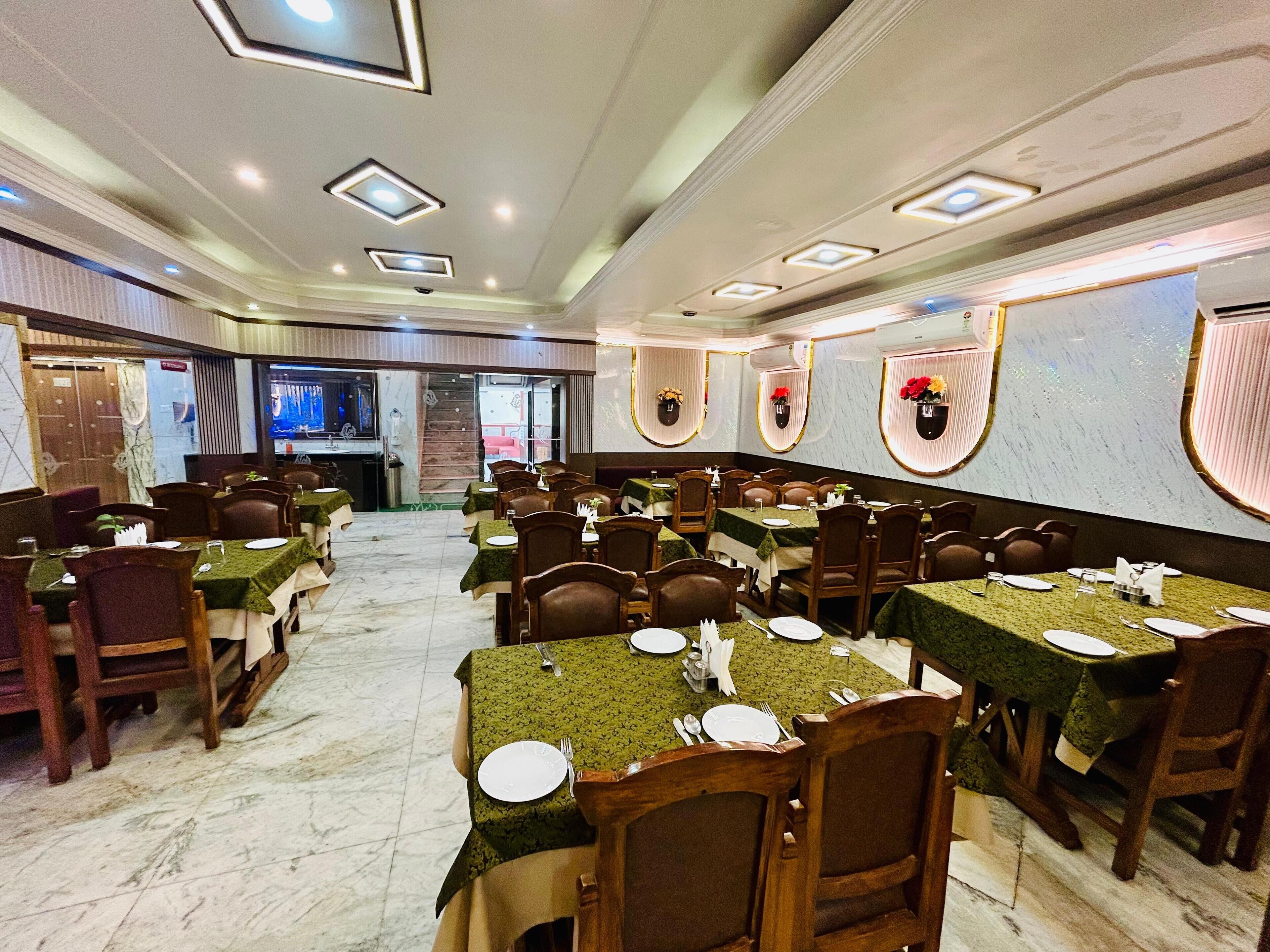 A spacious dining area with multiple tables and chairs, marble flooring, and a modern ceiling design.