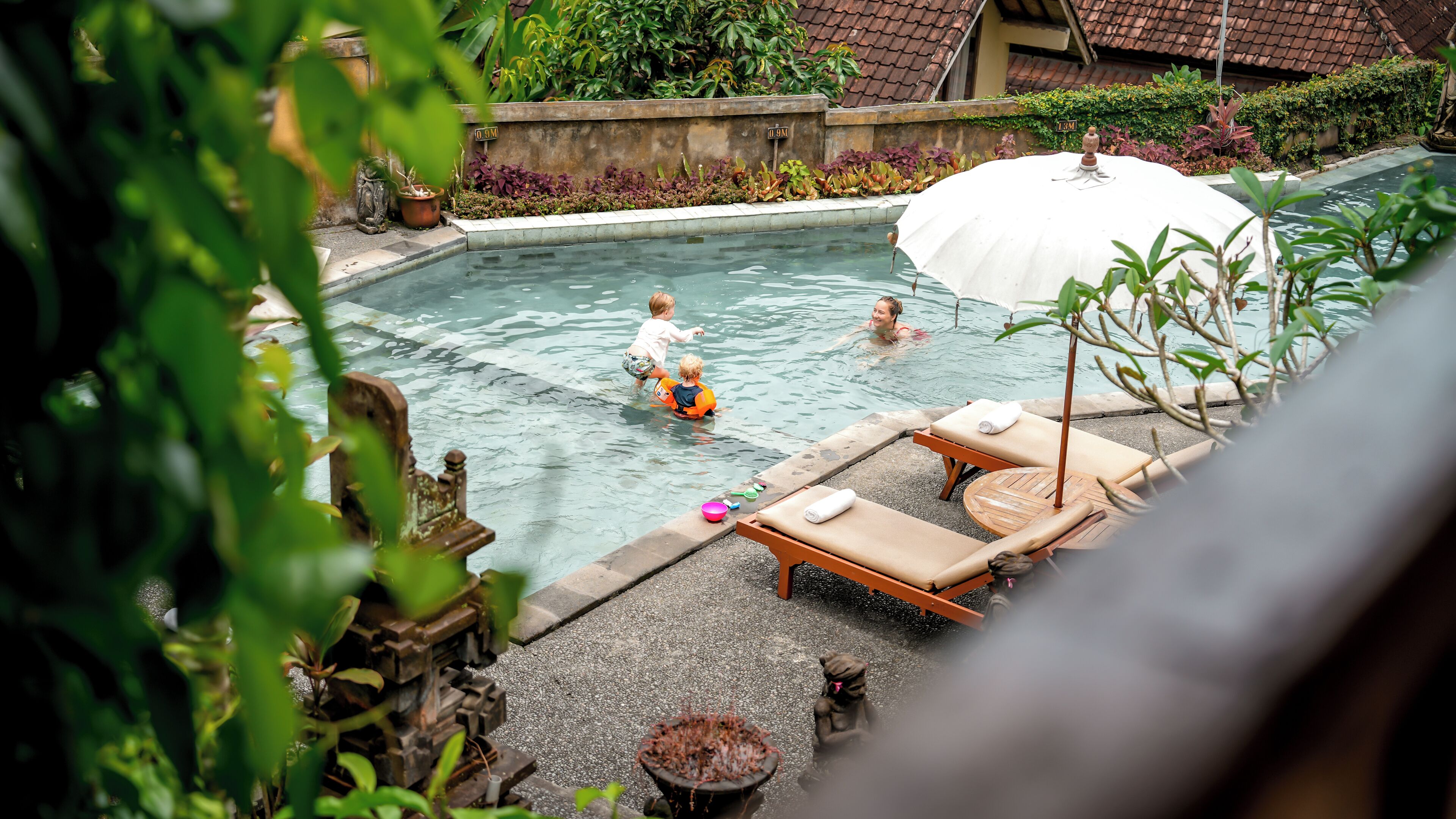 A swimming pool with lounge chairs and a sun umbrella.