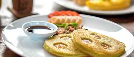 A dining table with a plate of pancakes, a cup of coffee, and a napkin holder.