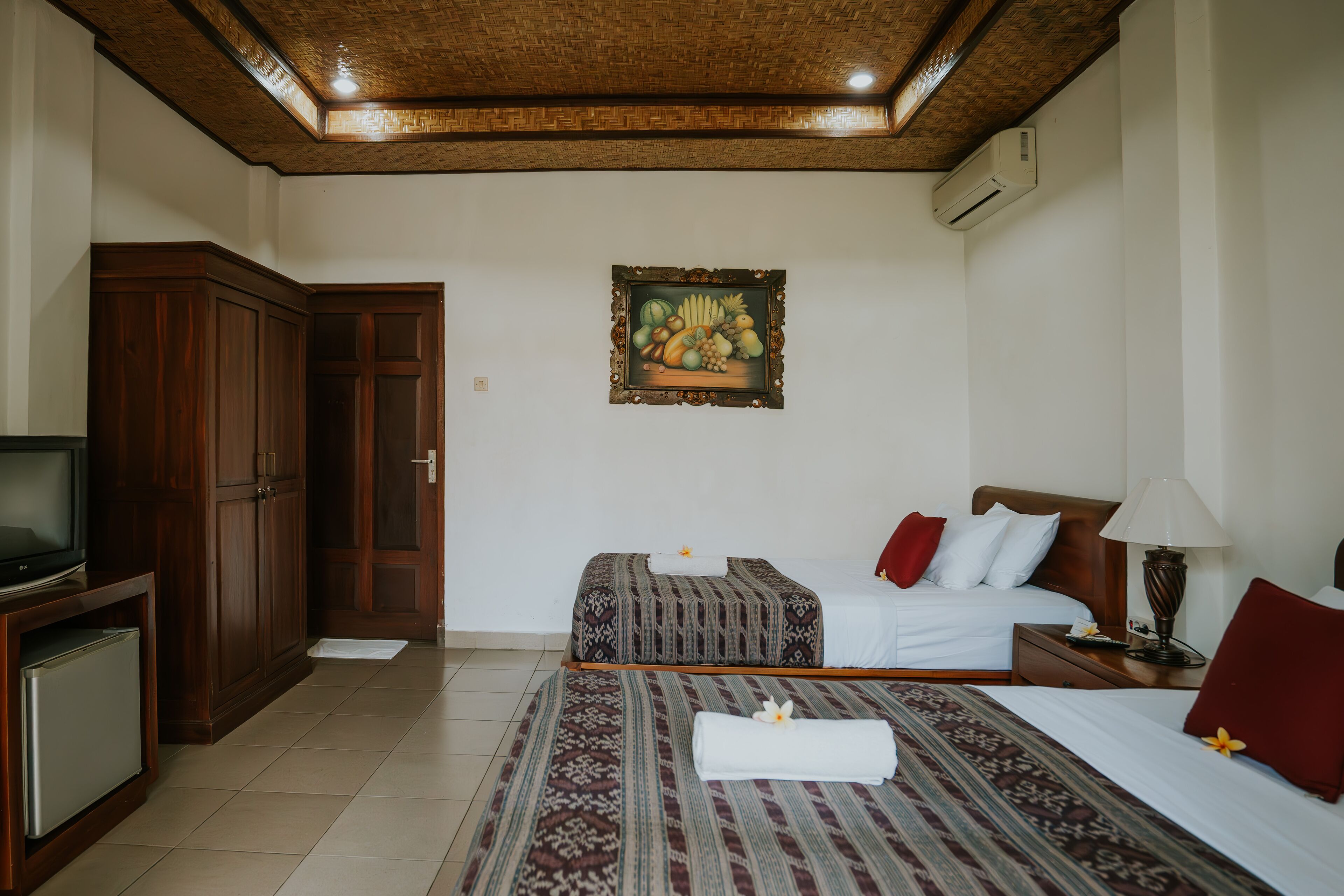A hotel room with two beds, a television, and a painting on the wall.