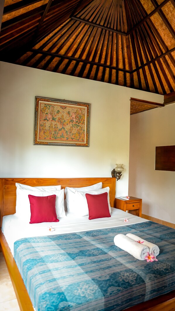 A hotel room with a bed, a nightstand, a lamp, and a painting on the wall.