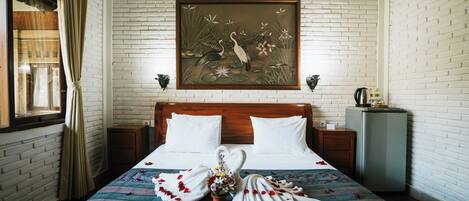 A hotel room with a bed, a nightstand, a wall-mounted painting, and a window with curtains.