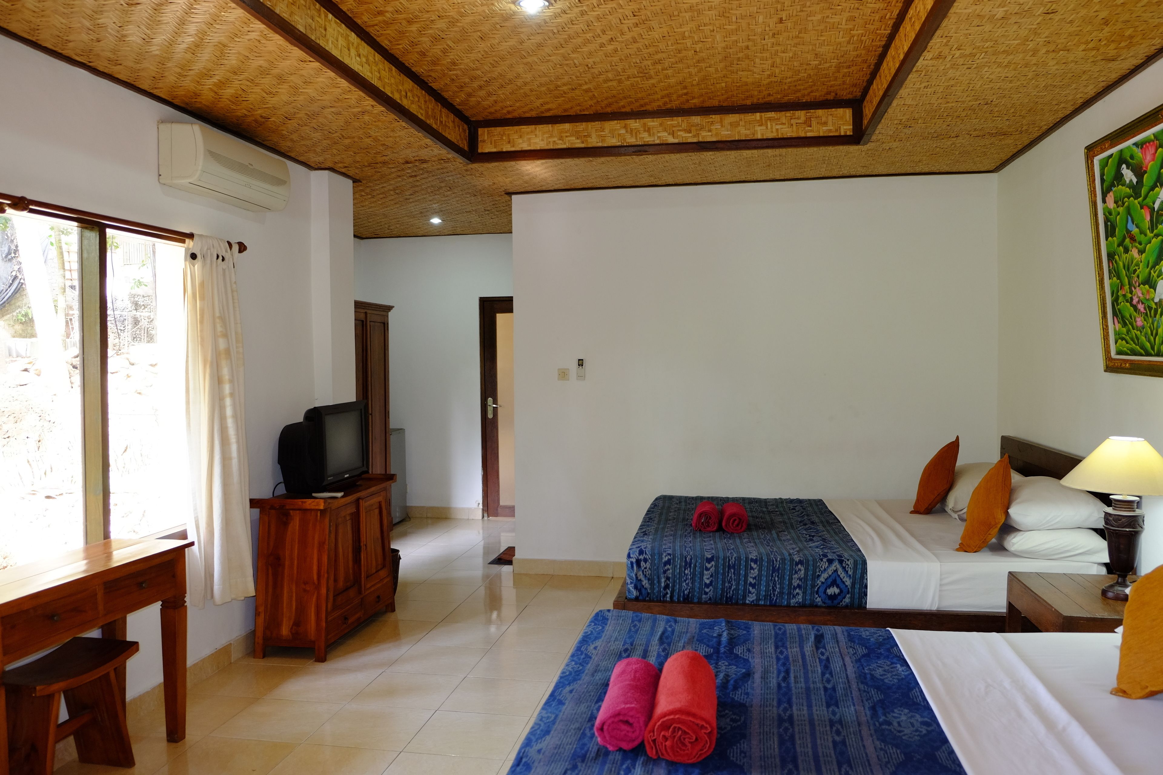 A hotel room with two beds, a TV, a desk, and a painting on the wall.