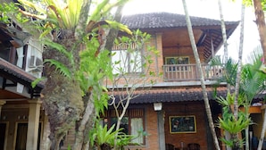 A two-story building with a balcony, surrounded by lush greenery and a traditional tiled roof. - Jati 3 Bungalows (Ubud)