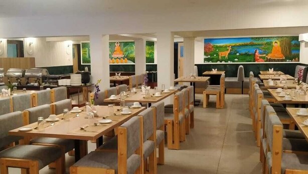 A restaurant with multiple dining tables and booths, equipped with table settings and a buffet area. - Hotel Sujata (Gaya)