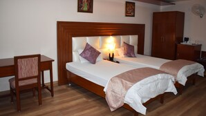 A double bed with a wooden headboard, two bedside tables, a chair, and a wardrobe. - Hotel Sujata (Gaya)