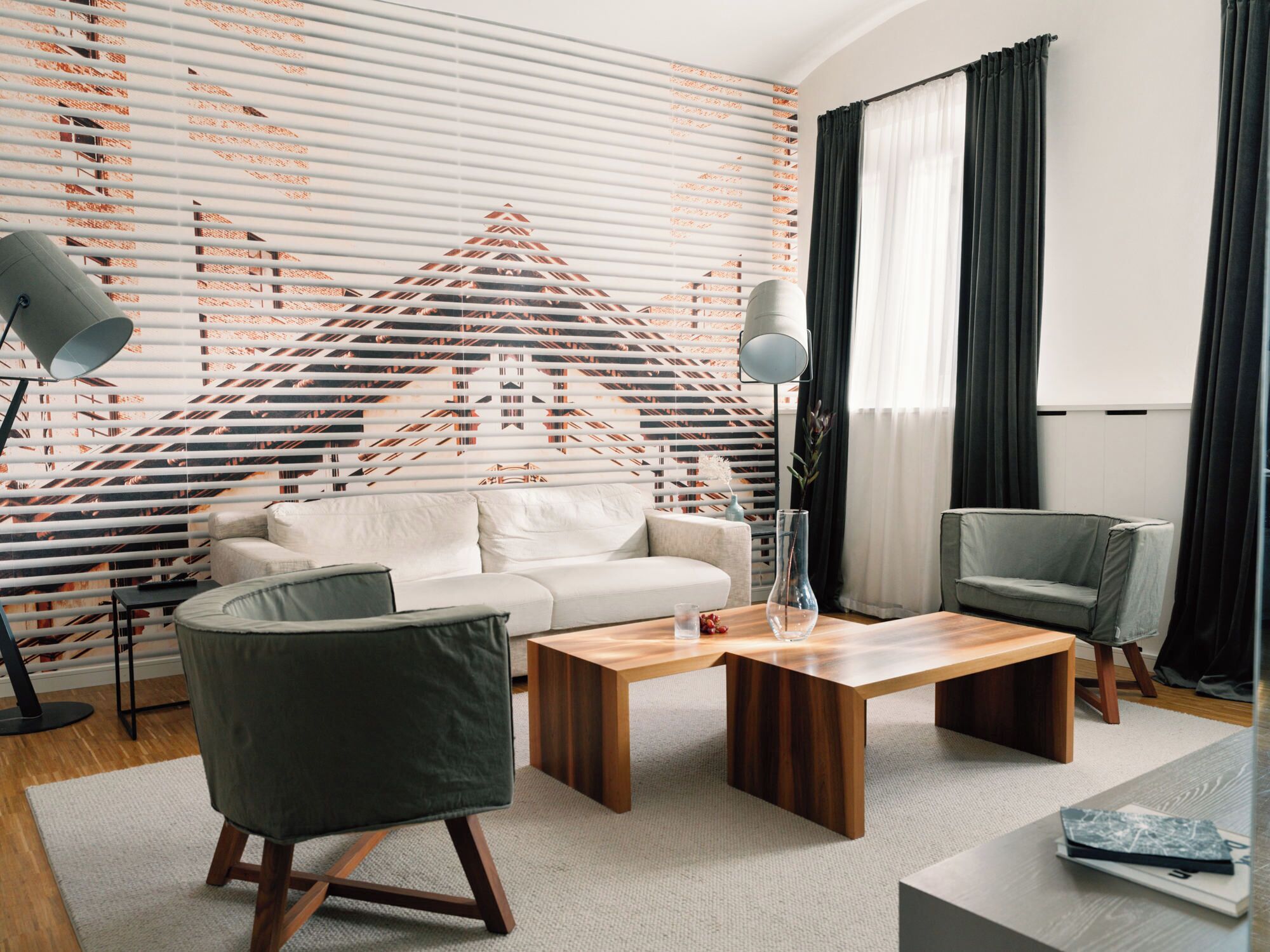 Ein modernes Wohnzimmer mit einer Couch, zwei Sesseln, einem Couchtisch und einer Lampe.