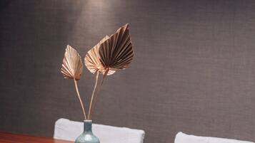 A dining table with a vase of dried flowers and a modern pendant light.