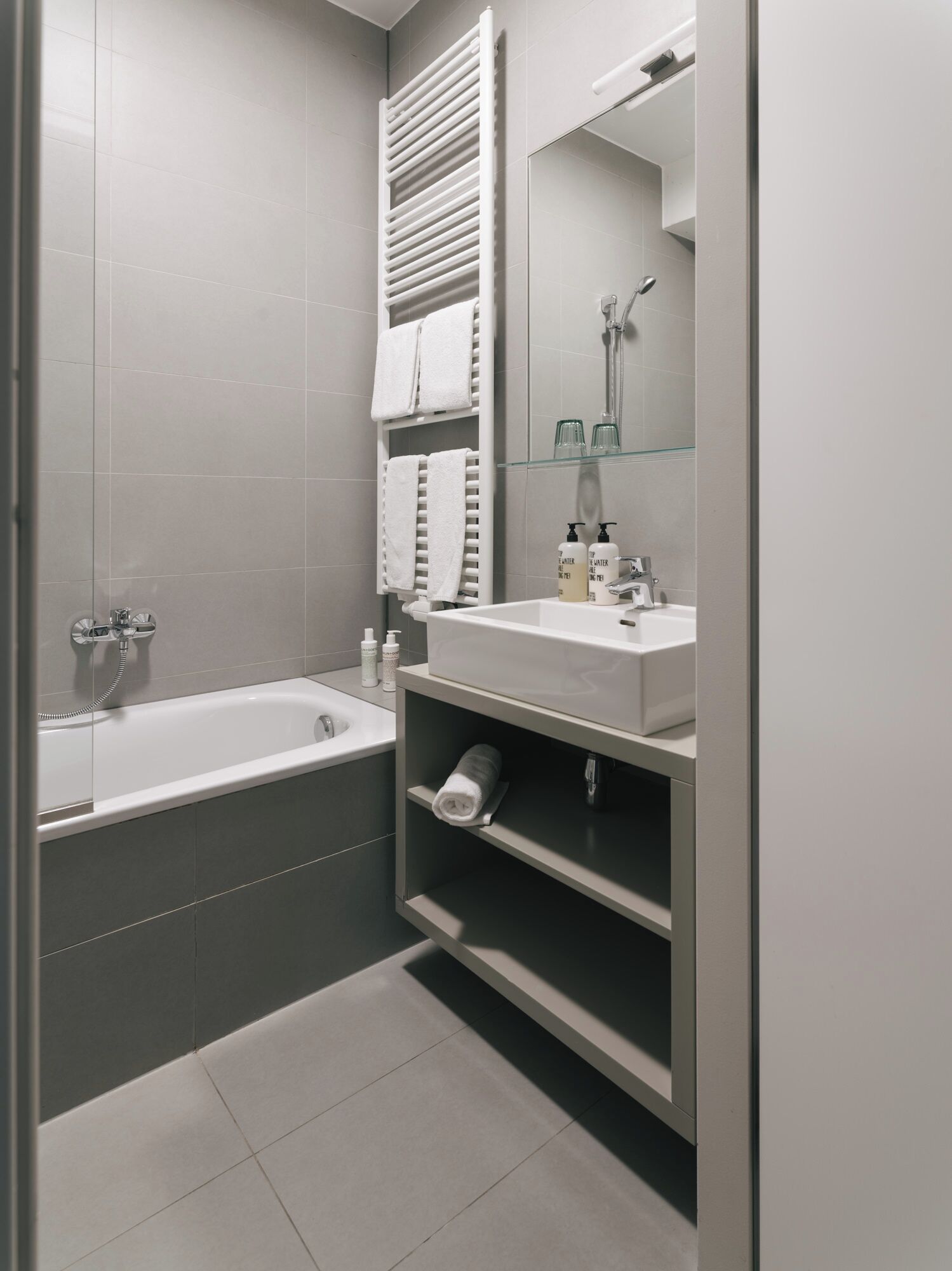 Ein modernes Badezimmer mit einer Badewanne, einem Waschbecken mit Spiegel und einem Handtuchhalter.