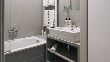 Ein modernes Badezimmer mit einer Badewanne, einem Waschbecken mit Spiegel und einem Handtuchhalter.