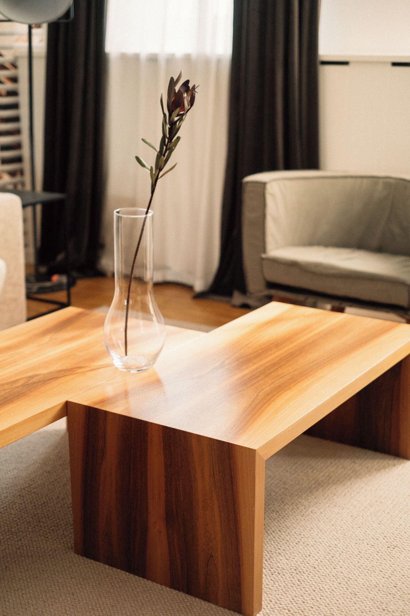 Una mesa de centro de madera con un florero transparente que contiene una planta.