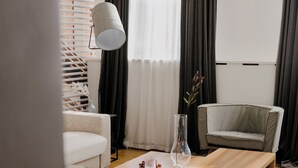 Una sala de estar moderna con sofá, sillón, mesa de centro de madera y lámpara de pie.