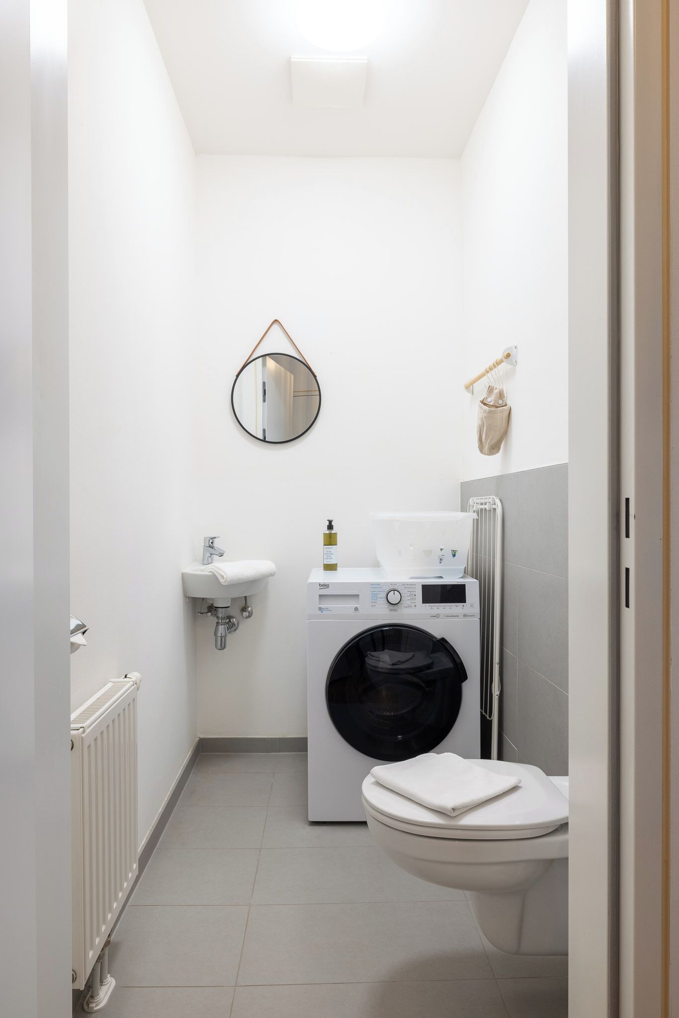 Un baño pequeño con lavamanos, inodoro y lavadora.