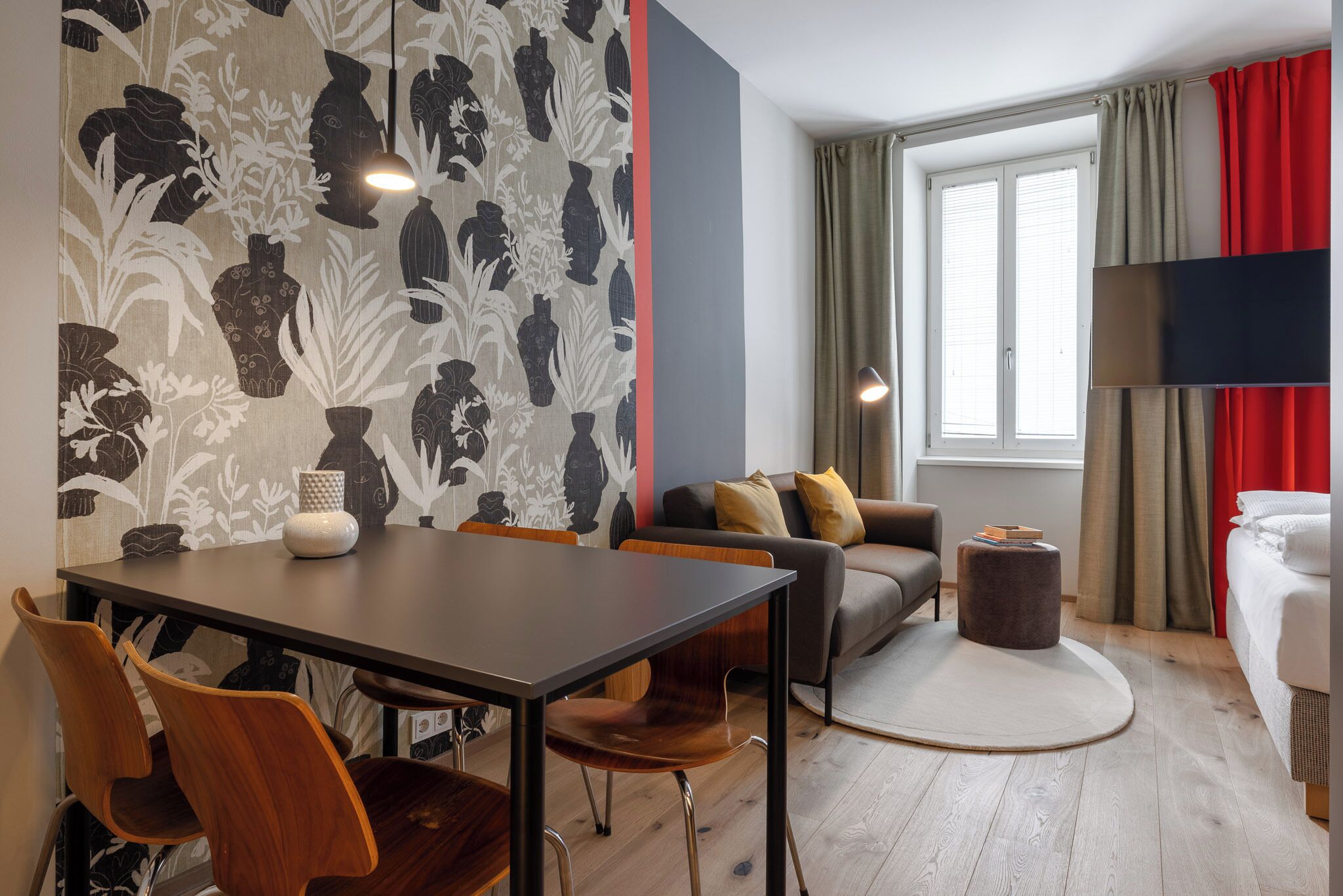 Une chambre d’hôtel comprenant un coin repas, un canapé, un tapis rond et un lit.