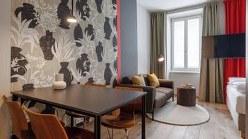 Une chambre d’hôtel comprenant un coin repas, un canapé, un tapis rond et un lit.