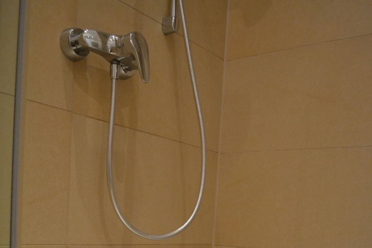 A bathroom with a shower, two bottles of soap, and a towel.