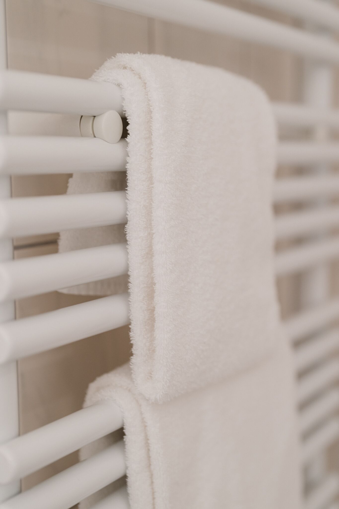 A white towel hanging on a white radiator.