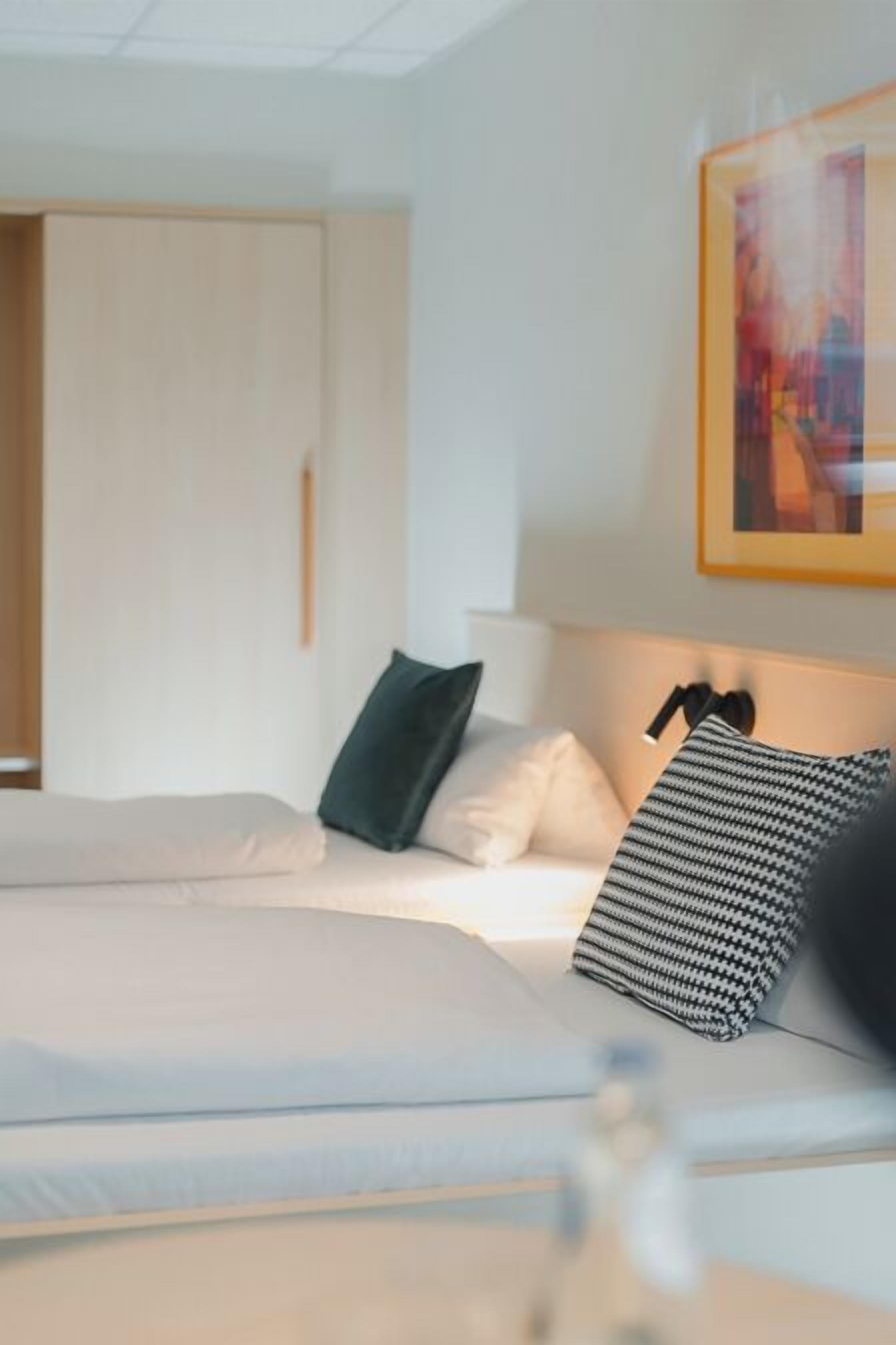 Una habitación de hotel con una cama, una mesita de noche, una lámpara y un cuadro en la pared.