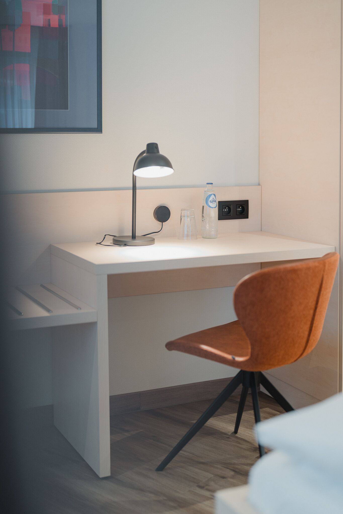 A modern workspace with a desk, chair, lamp, and a water bottle.