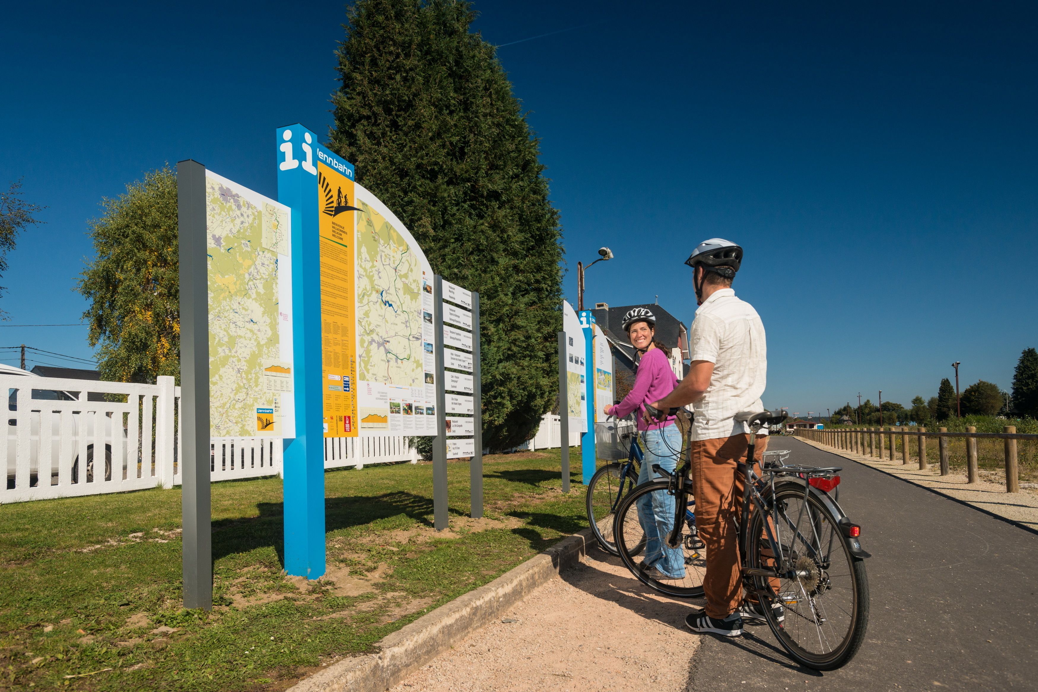 A man and a woman standing next to a bicycle, with a map sign in the background.