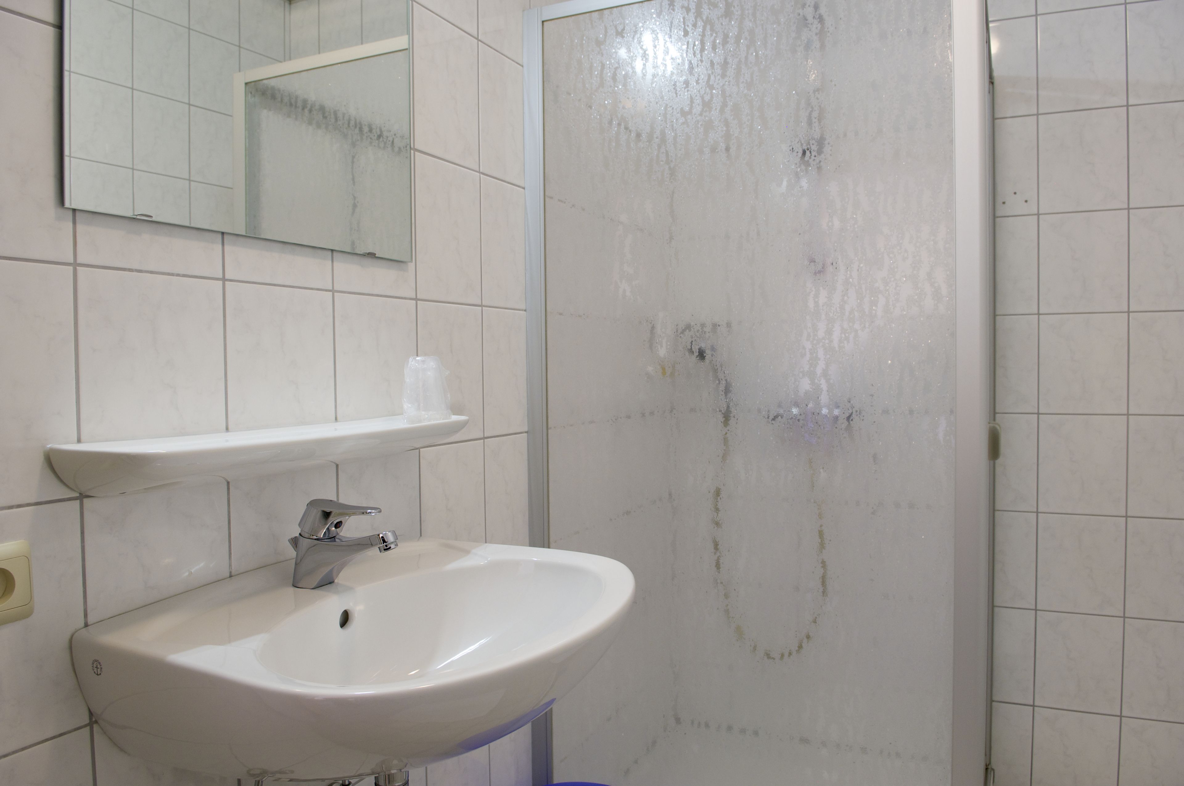 A bathroom with a white sink, a mirror, and a shower area.