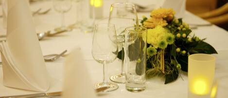 Una mesa dispuesta para comer, con copas transparentes, una vela y un centro de mesa floral.