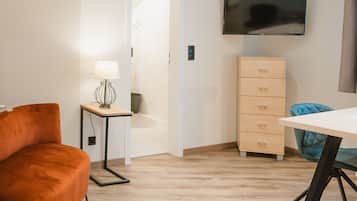 Una sala de estar moderna con suelo de madera, un sofá, una mesa, una lámpara, un televisor y un mueble.