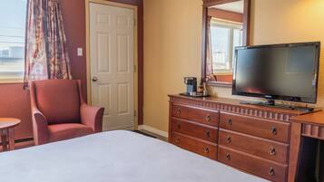 A hotel room with a bed, a wooden dresser, a television, and a chair.
