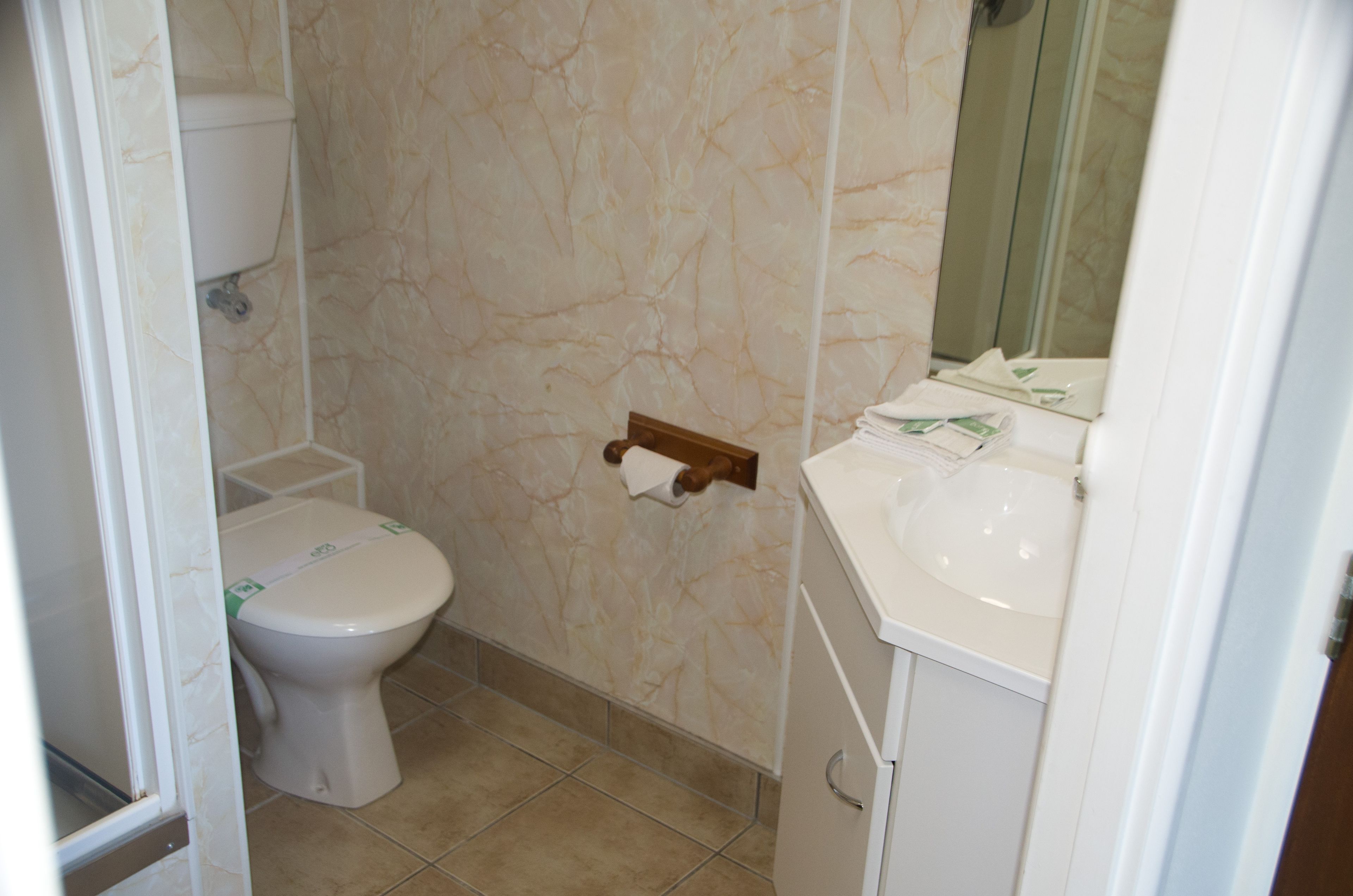 Un baño con inodoro, lavamanos y espejo.