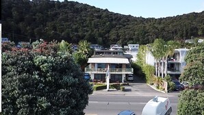 Ein zweistöckiges Gebäude mit Balkon, umgeben von üppiger Vegetation und einer Bergkulisse.