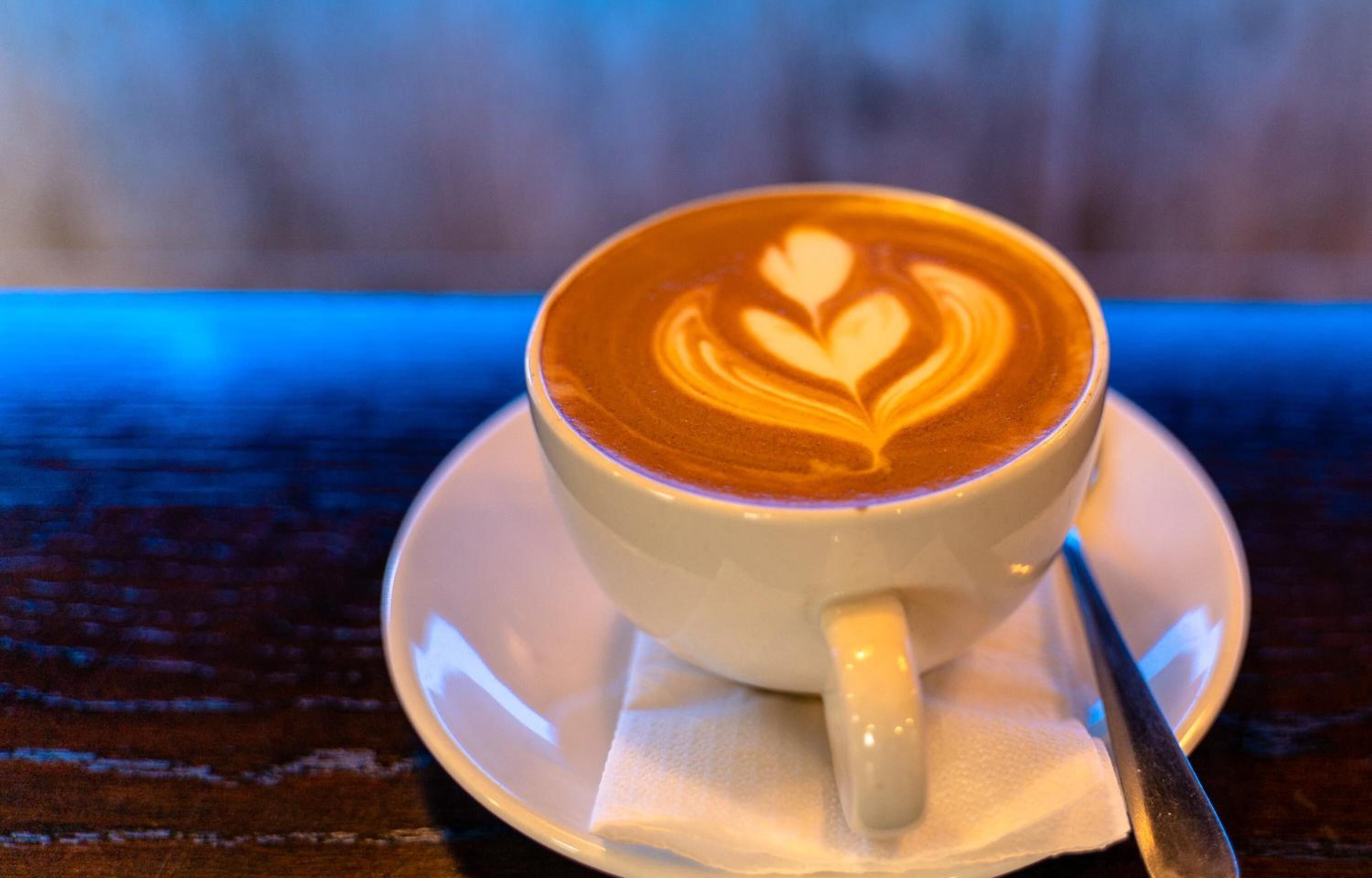 A cup of coffee with latte art on a saucer.