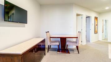 A modern dining area with a wooden table and chairs, a bench, and a flat-screen TV mounted on the wall.