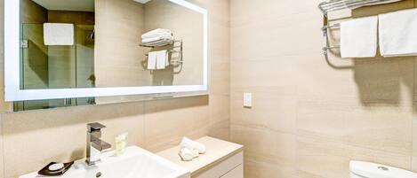 A modern bathroom with a large mirror, a sink, a vanity, and a towel rack.