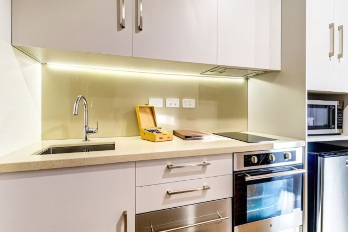 A modern kitchen with a stainless steel sink, a microwave, and a built-in oven.