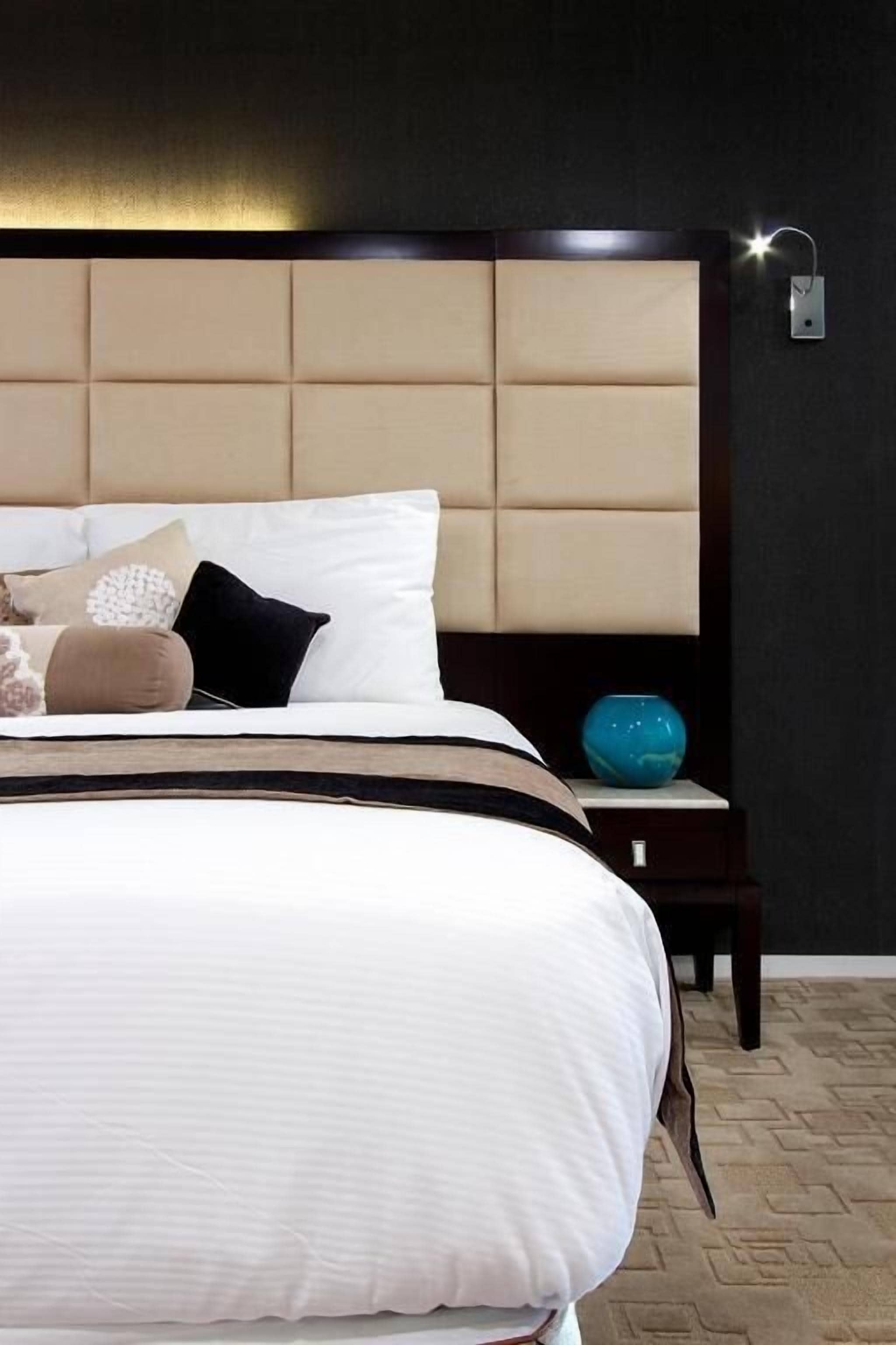 A bedroom with a large bed, a headboard, a bedside table, and a nightstand.