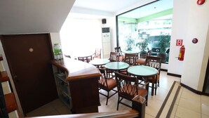A dining area with multiple round tables and chairs, a water dispenser, and a fire extinguisher on the wall.