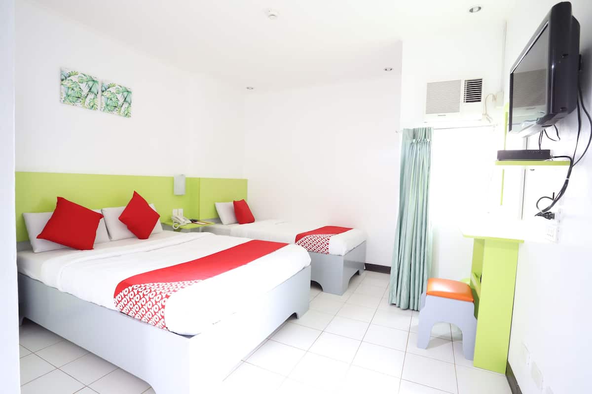 A hotel room with two beds, a desk, a television, and a window with curtains.