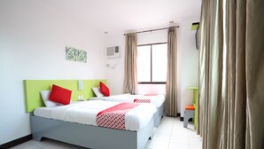 A hotel room with a bed, curtains, a window, and a small table.